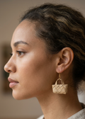 Woman wearing a woven earring with a blurred background
